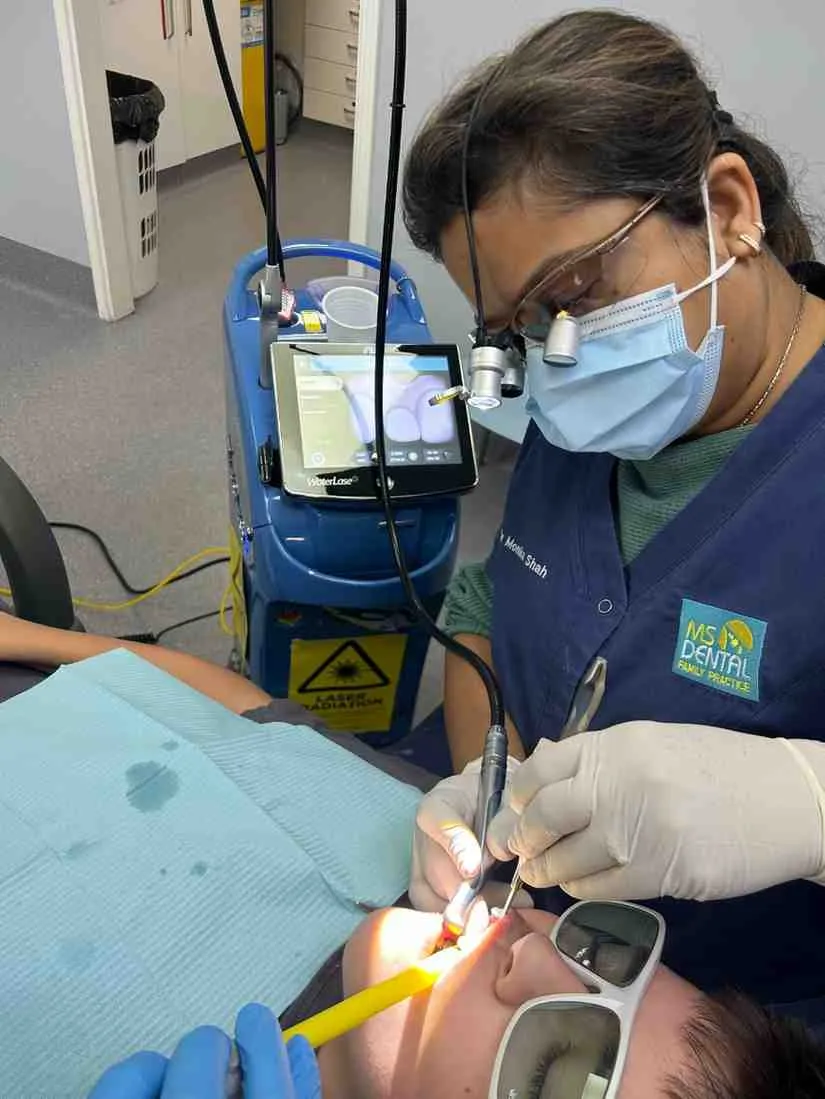 Dr Monika Shah treating a patient, with laser equipment beside the chair